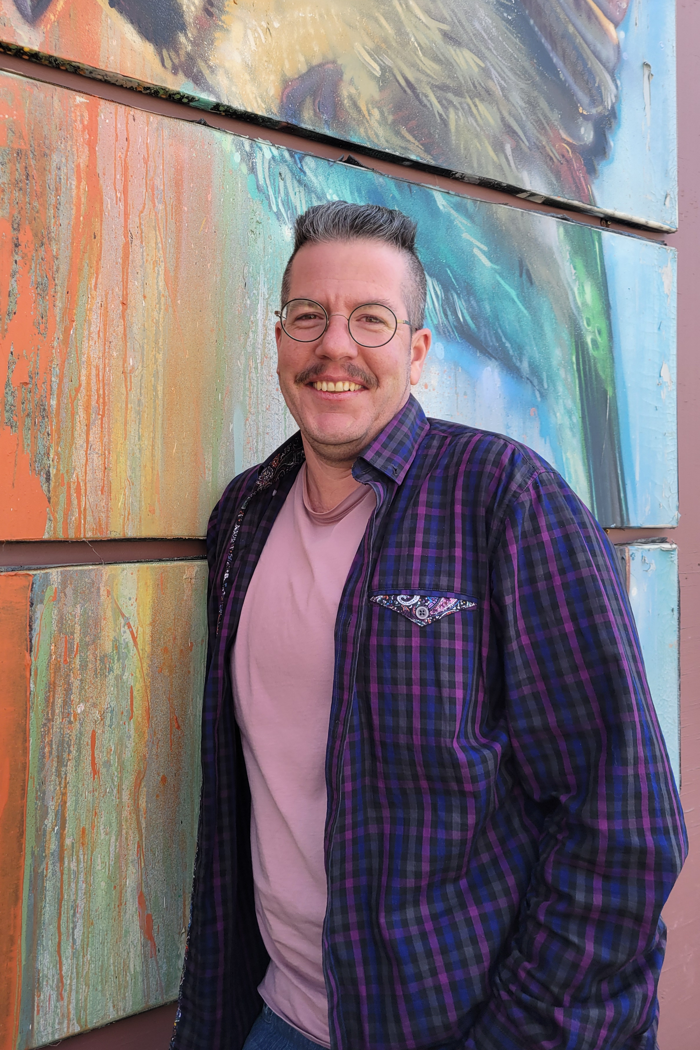 Sol a les cheveux courts gris foncé et porte une chemise mauve