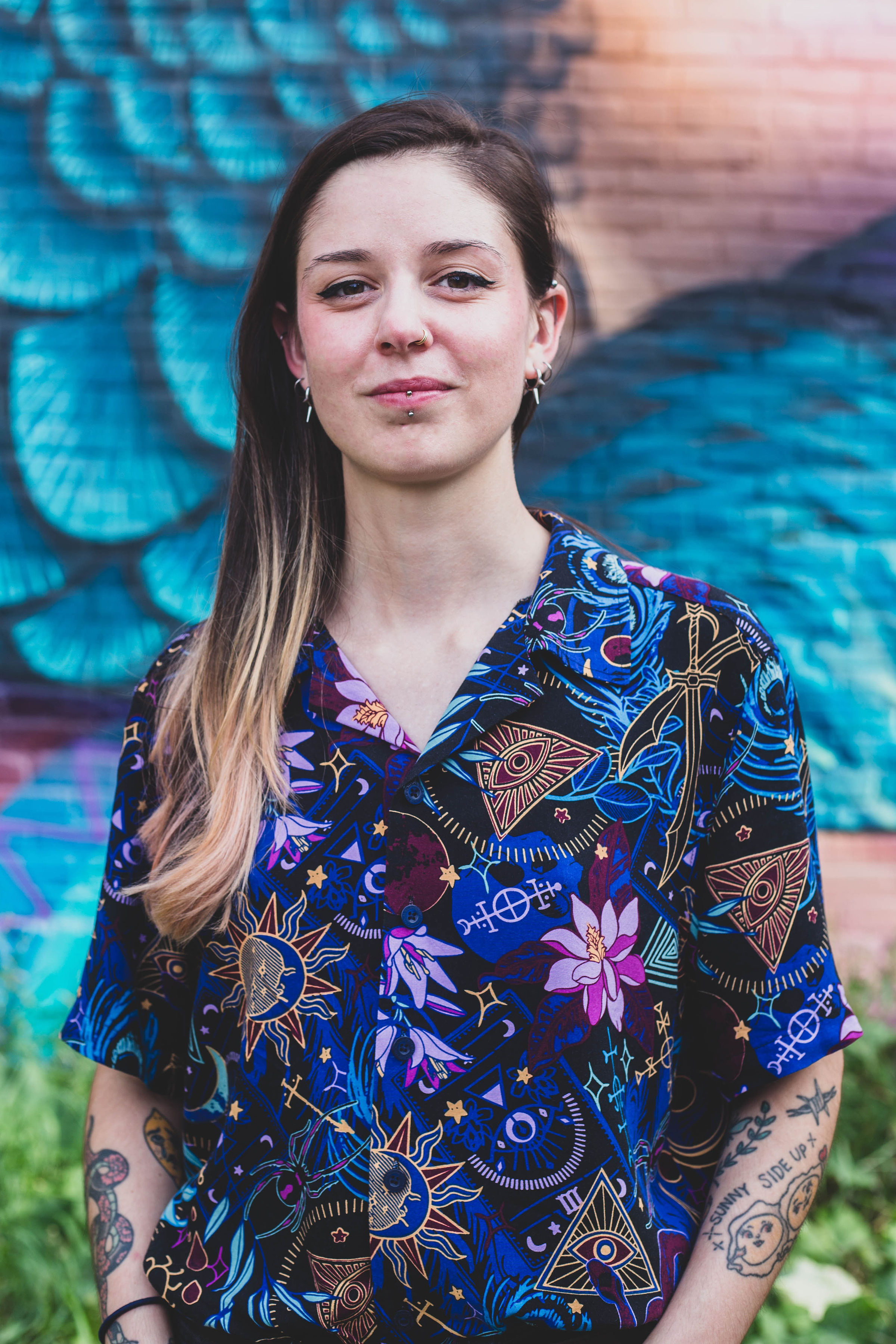 Anais has long brown hair and sometimes wears glasses. In the photo she is also wearing a blue shirt with psychedelic motifs.