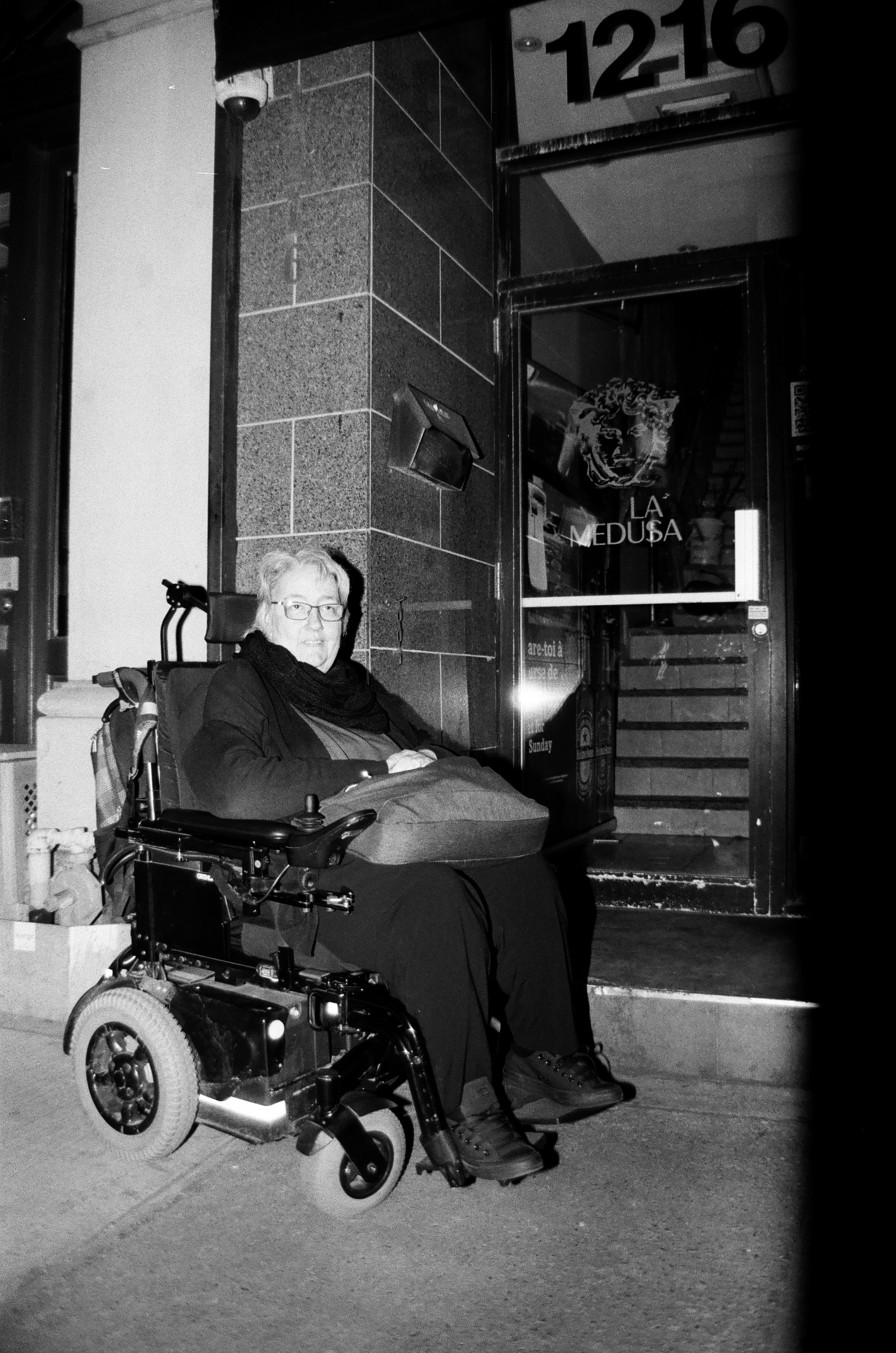 Manon de trouve devant l'entrée d'un bar ou elle devait entrer pour un 5 à 7 mais que malheureusement l'entrée n'était pas accessible pour un  fauteuil roulant. Dans cette photo il y a une entrée avec des escaliers.